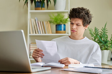 Serious young guy reading letter, paper document