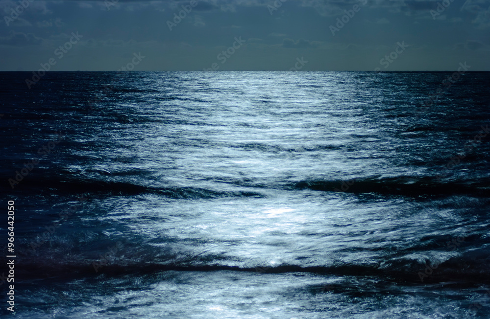 Wall mural Moonlight reflection on the sea at night, creating a background.