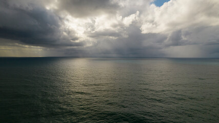 Obraz premium Storm on the sea with sun rays between clouds. Aerial photography