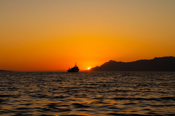 An old sailboat sailing against the background of a red sunset. Beautiful summer landscape. Makarska, Dalmatia, Croatia
