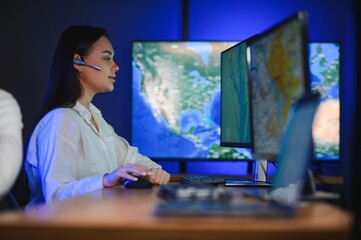 Friendly smiling woman call center operator with headset using computer at office
