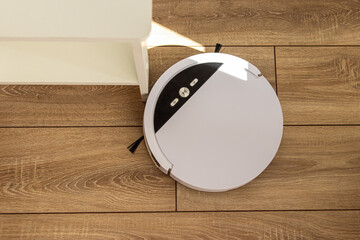 Robot vacuum cleaner vacuums in living room or bedroom. Robot vacuum cleaner and wooden furniture. Top view