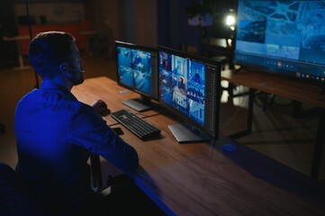 Male security guard monitoring modern CCTV cameras indoors