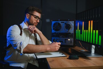 Secret agent listens on the reel tape recorder. Officer wiretapping in headphones