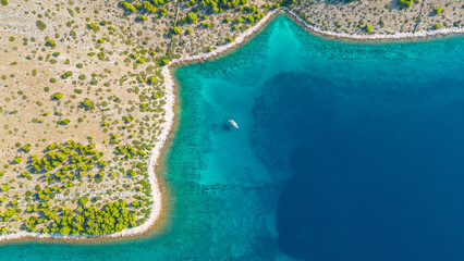 An aerial view of a serene bay on Otok Žut, located near the Kornati Islands in Croatia. The bay, surrounded by lush greenery and rocky shores, offers a tranquil retreat in the Adriatic Sea