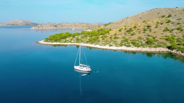 An aerial view of a serene bay on Otok Žut, located near the Kornati Islands in Croatia. The bay, surrounded by lush greenery and rocky shores, offers a tranquil retreat in the Adriatic Sea