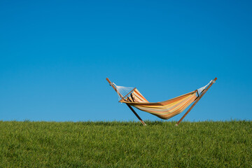 un hamac orange sur fond de ciel bleu et d'un champ vert