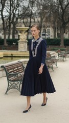 Fototapeta premium Elegant Woman in Navy Pleated Dress with Pearl Accents