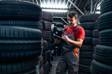 Warehouse worker checking tire inventory and holding checklist. © littlewolf1989
