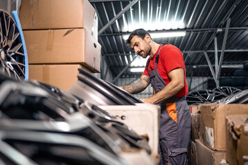 Warehouse worker arranging wheel rims for sale.