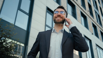 Joyful happy man Caucasian businessman talking mobile phone in city funny carefree conversation outdoors male business employer office worker ceo manager speak cellphone laughing near office company