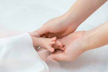 Gentle mother hand holding the legs of a newborn baby.