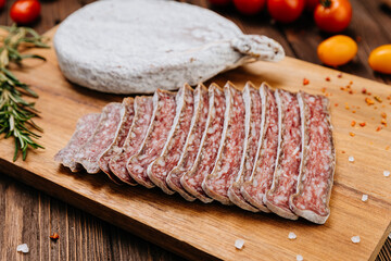 Traditional dry cured sausage slices on board with spices and herbs, perfect for food photography
