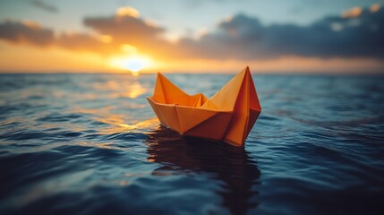 A small paper boat floats on the water at sunset.