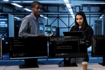 Technicians in data center using devices to check for server performance issues arising due to high...