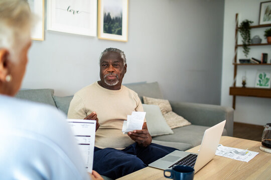 Diverse senior couple reading bills on the couch at home