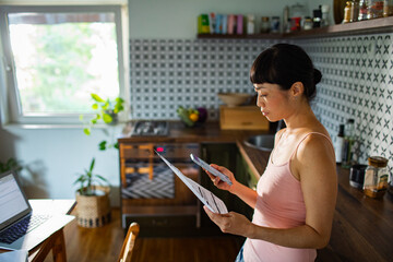 Stressed woman reviewing bills and financial documents at home