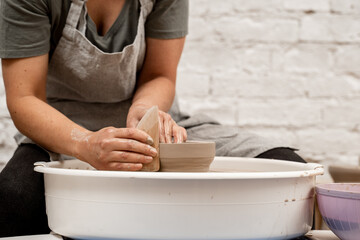 Making smooth edges of pottery with a wooden scraper and a pottery wheel. Cutting the lines on sides of a clay product with a wooden scraper.