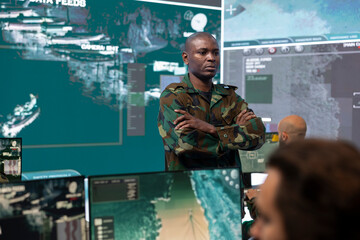 Portrait of army commander in military camouflage uniform supervising his crew, captain overseeing...