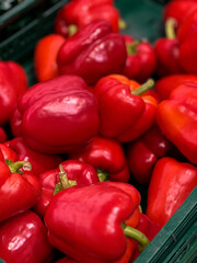 Close up of fresh red bell peppers in a basket on a shelf at a grocery store