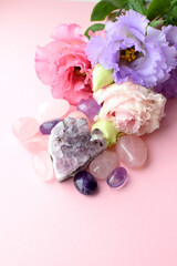 Beautiful lilac eustoma flowers (lisianthus) in full bloom with natural stones amethyst and rose quartz. Flowers and semi-precious stones on a pink background.