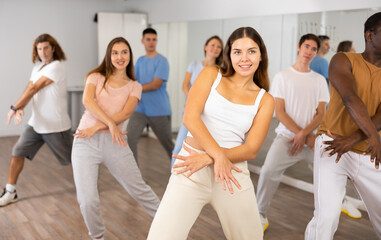 Fototapeta premium Energetic women and man performing modern dance in fitness studio