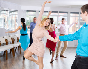 Cheerful female amateur dancer practicing vigorous playful swing in pair with guy during dance...