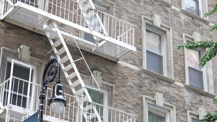 Fototapeta premium New York City classic building architecture. Urban residential house exterior. Real estate property in USA. Typical brick facade in United States. Fire escape, emergency ladder exit.