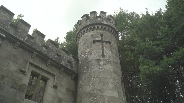 Ancient tower with a cross on the tower. Ballysaggartmore Towers in 4k