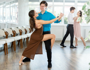Fototapeta premium Couple of young guy and young women dancing tango dance in studio