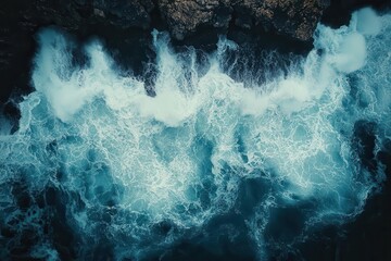 Fototapeta premium aerial view of azure ocean waves crashing against rugged rocky shore foamy white surf contrasting with dark rocks capturing the raw power of the sea