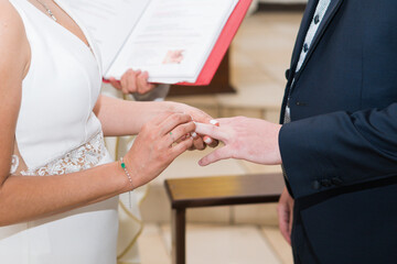 Obraz premium Hispanic bride and groom are getting married and the bride puts a ring on the groom's finger.