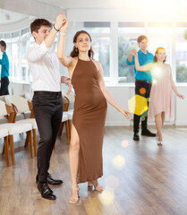 Happy girls paired with guys dance waltz in dance class