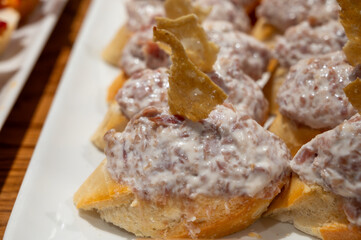 Typical snacks of Basque Country, pinchos or pinxtos skewers with small pieces of bread, fish, sea food, sweet green pepper served in bar in San-Sebastian or Bilbao, Spain