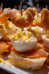 Typical snacks of Basque Country, pinchos or pinxtos skewers with small pieces of bread, fish, sea food, sweet green pepper served in bar in San-Sebastian or Bilbao, Spain