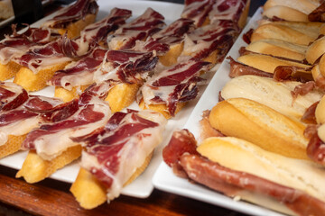 Typical snacks of Basque Country, pinchos or pinxtos skewers with small pieces of bread, fish, sea food, sweet green pepper served in bar in San-Sebastian or Bilbao, Spain