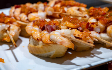 Typical snacks of Basque Country, pinchos or pinxtos skewers with small pieces of bread, fish, sea food, sweet green pepper served in bar in San-Sebastian or Bilbao, Spain