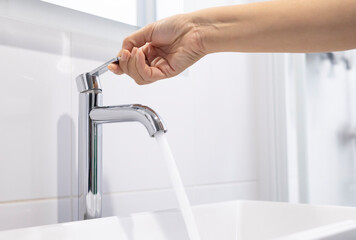 close up Woman open pull chrome faucet washbasin to washing hand soap for corona virus at water...