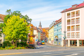 Obraz premium A street of colorful buildings with the dome of the Deutschhauskirche, or Deutschhaus Church, in view along the banks of the Main River in Wurzburg, Germany.