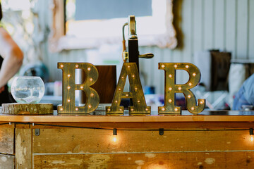 Rustic Bar Sign with Illuminated Marquee Letters at Outdoor Event