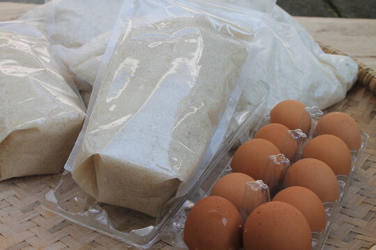 Rice, sugar and eggs in woven bamboo called tampah on a wooden table

