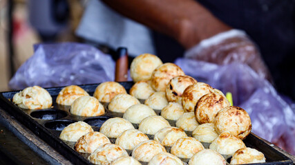 Close-up of Takoyaki balls being grilled to perfection on a hot plate. The golden brown color and round shape highlight the deliciousness of this popular Japanese street food