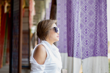 Fototapeta premium Asian mid adult woman holds woven fabric which was decorated on ceiling of local cafe for tourist watching and taking photos, soft focus, happiness of humans concept.
