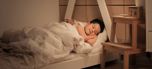 Cute little Asian boy sleeping in bed