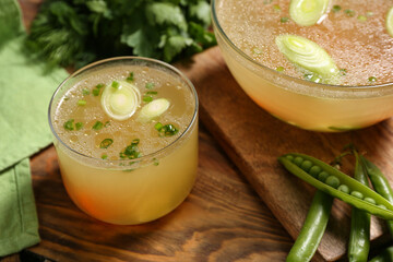 Bowls of tasty vegetable broth on wooden background