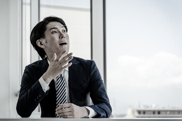 オフィスに座る若いアジア人ビジネスマン
