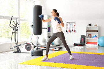 Fototapeta premium Young woman in boxing gloves training in gym. Concept of self defense