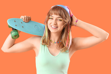 Young woman with skateboard on orange background