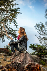 Side profile of a woman sitting on a log in a forested area