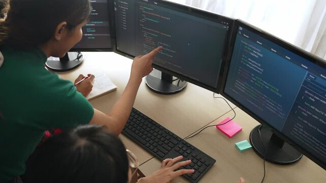 Slow motion back end software developer engineer for computer programming working together on debugging writing computing code, solving complex algorithms display on monitor in office. Burgeoning